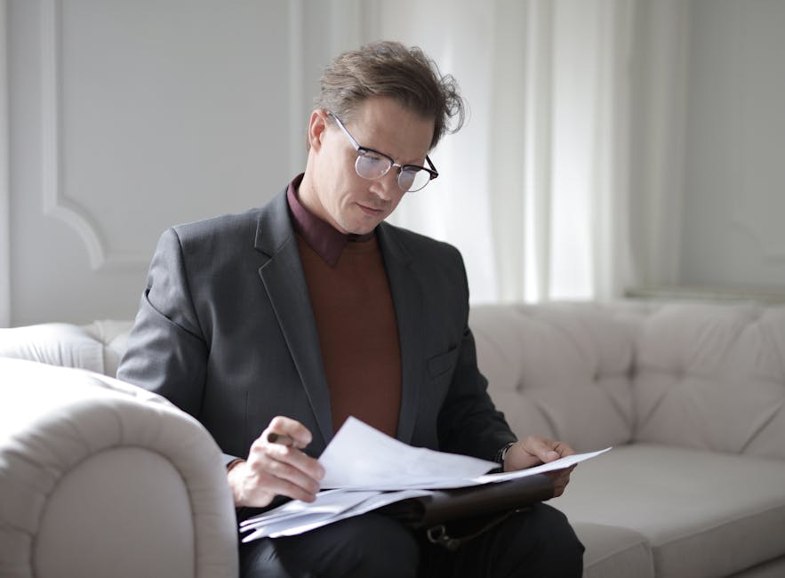 pexels-photo-3760514-3760514 Elegant adult man in jacket and glasses looking through documents while sitting on white sofa in luxury room