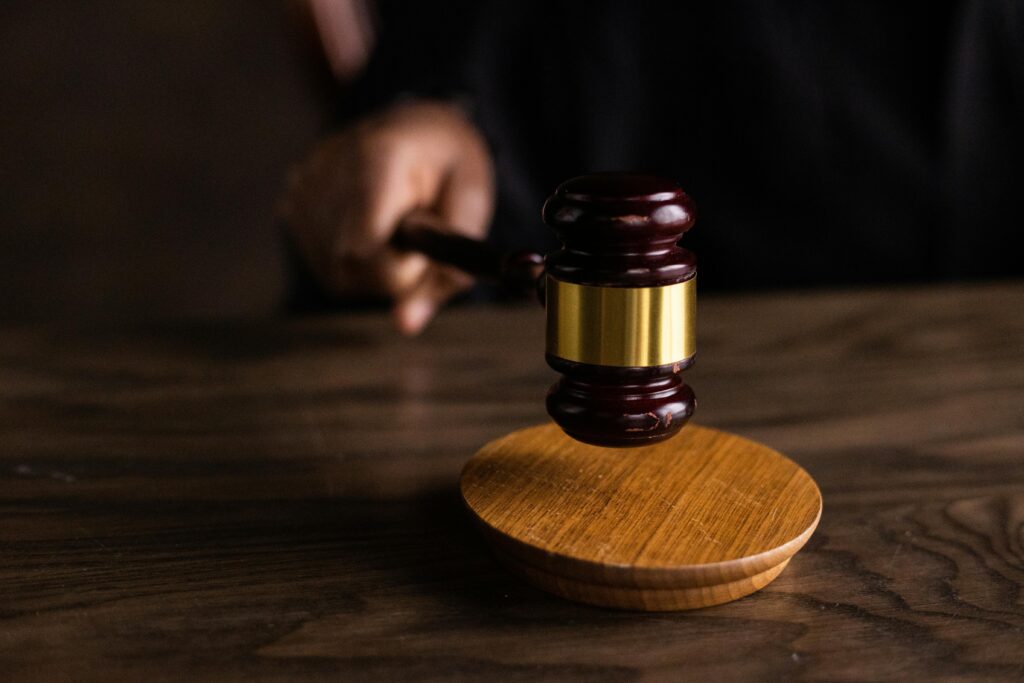 pexels-photo-6077326-6077326 A gavel striking a sound block, symbolizing justice and legal authority in a courtroom setting.